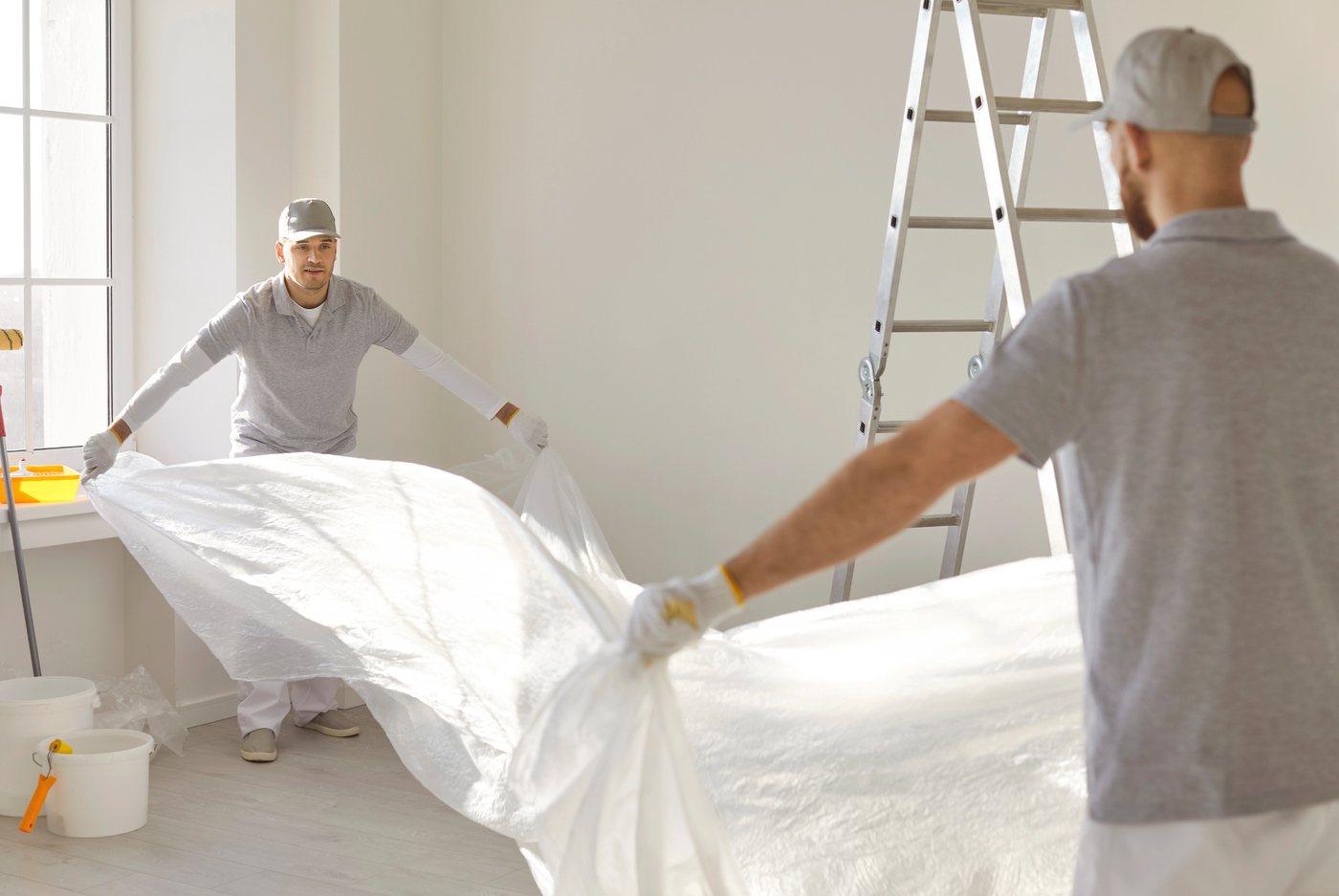 Maler deckt Möbel vor den Renovierungsarbeiten sorgfältig ab