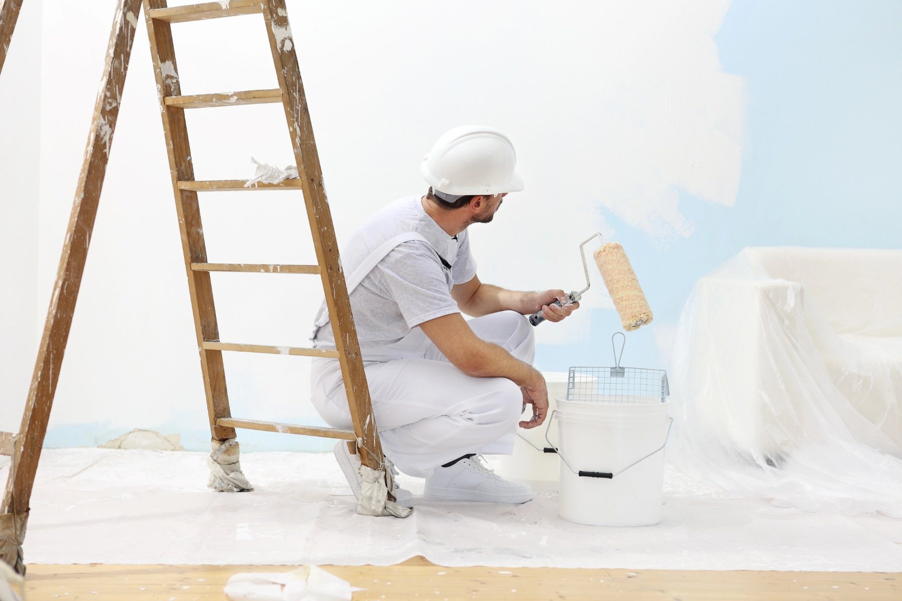 Maler streicht eine Wand fachgerecht mit weißer Farbe